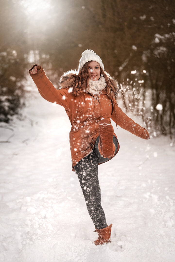 Winter Fotoshooting Mädchen mit weißer Mütze und mit brauner Jacke